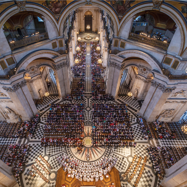 The interior view of St Paul's Cathedral from above, looking down from the dome. Hundreds of people are seated.