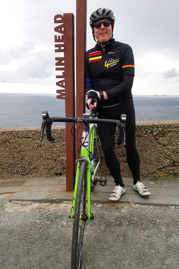 Barry, standing by his green bike, dressed in black.