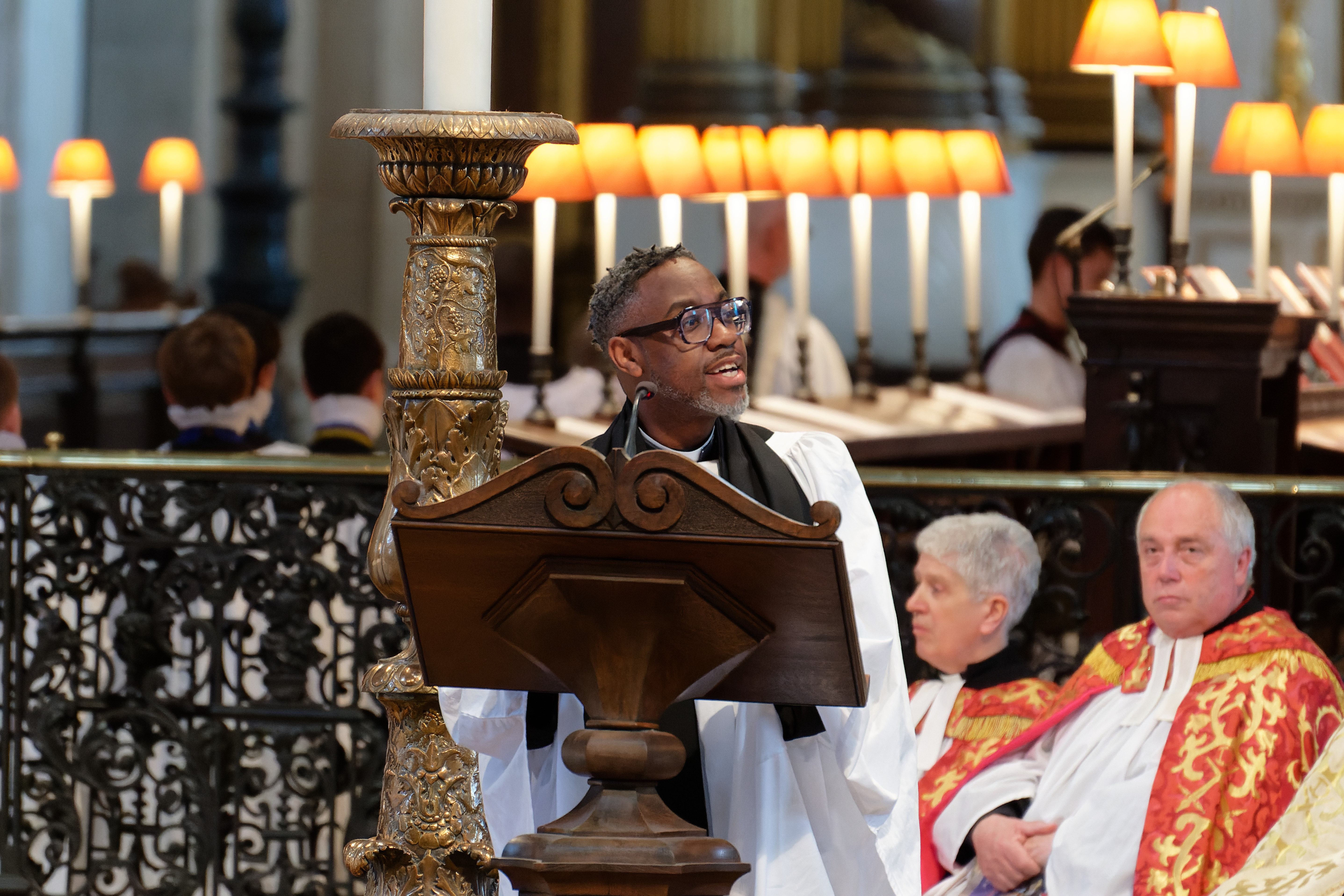 The Revd Azariah France-Williams, standing at a lectern and delivering a lesson.