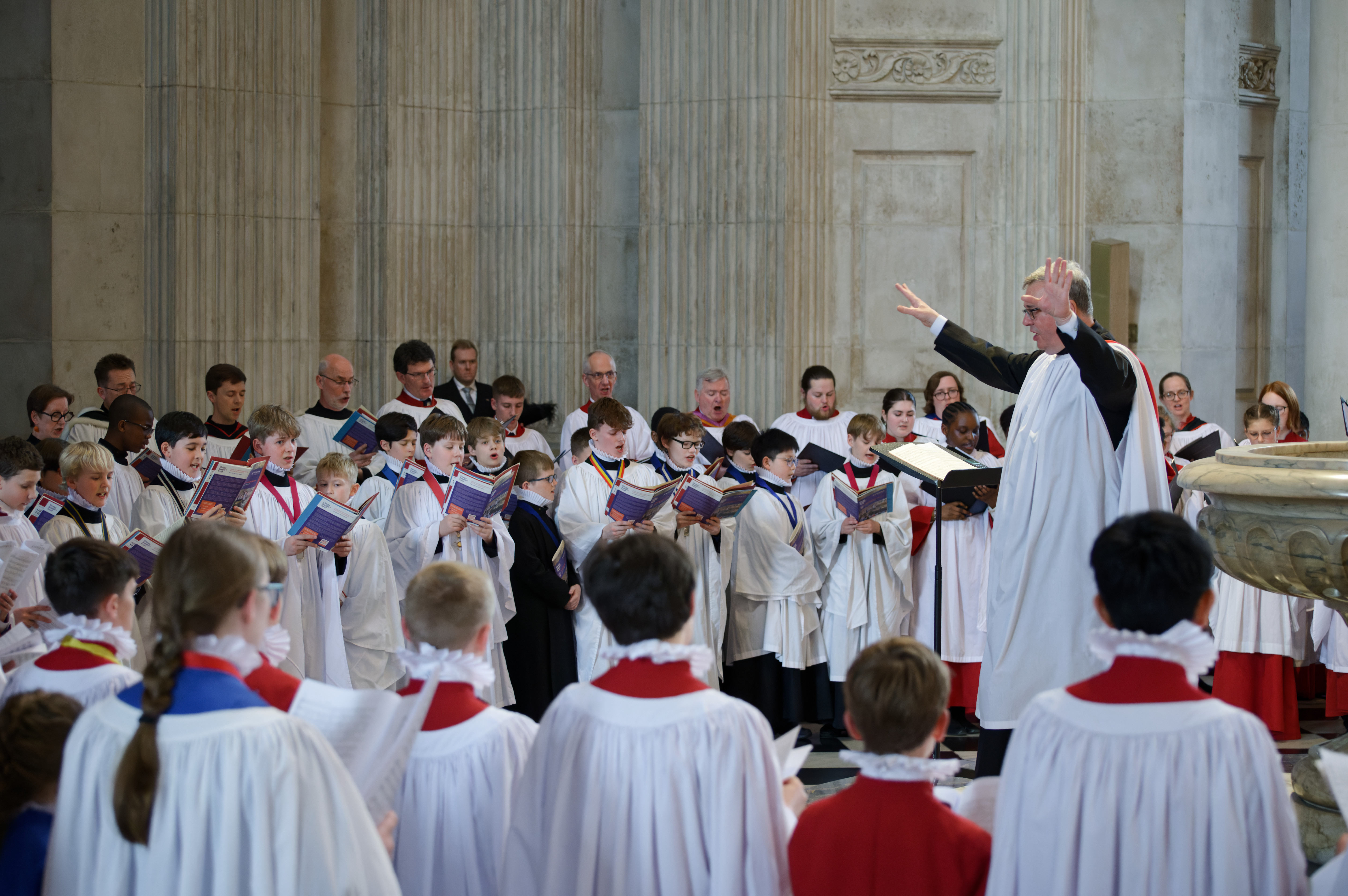 The combined choirs, lead by a choirmaster, performing in a semi-circle by the West Doors.