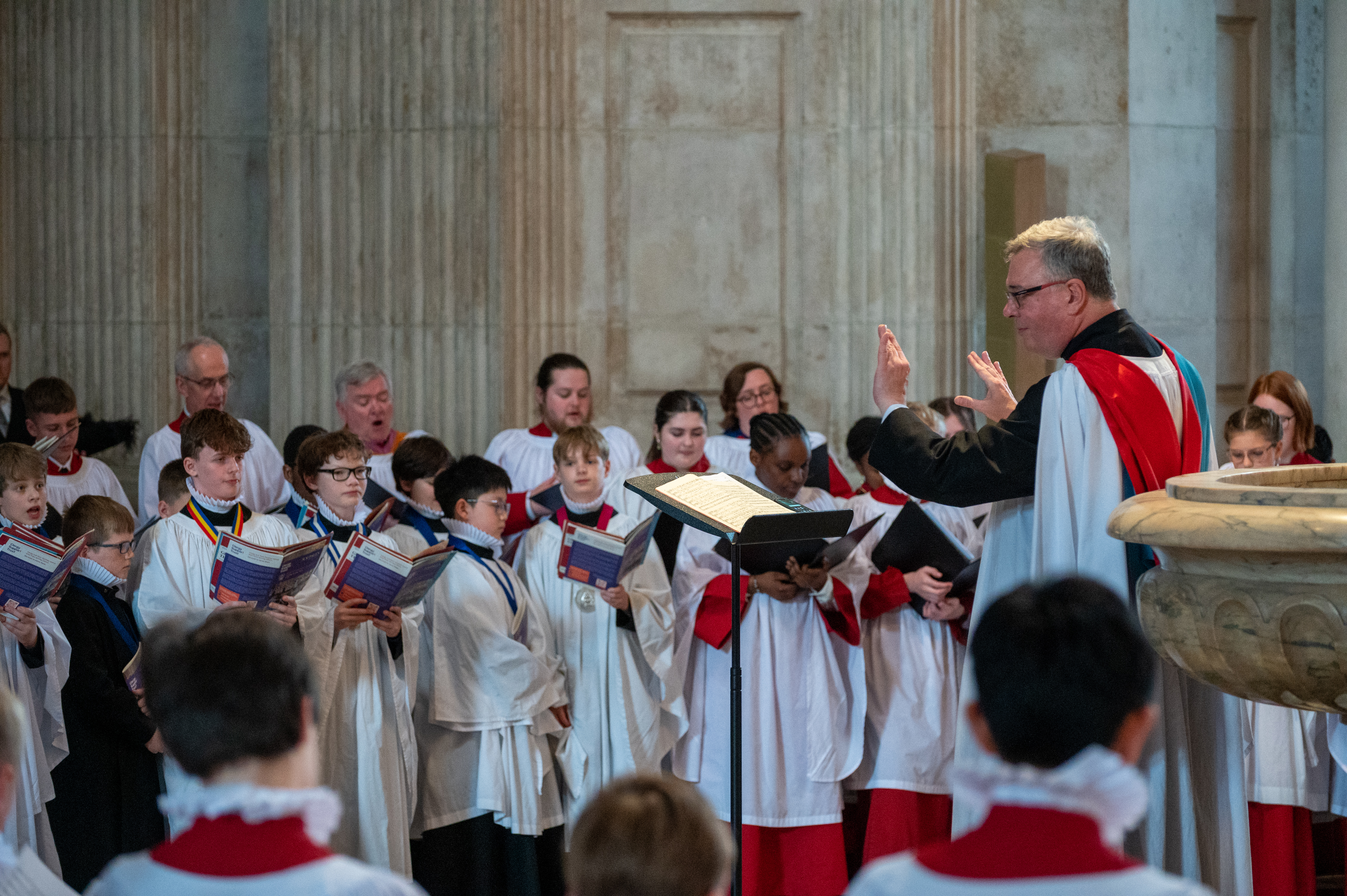 Andrew Carwood, Director of Music at St Paul's Cathedral, leading the three combined choirs in song.