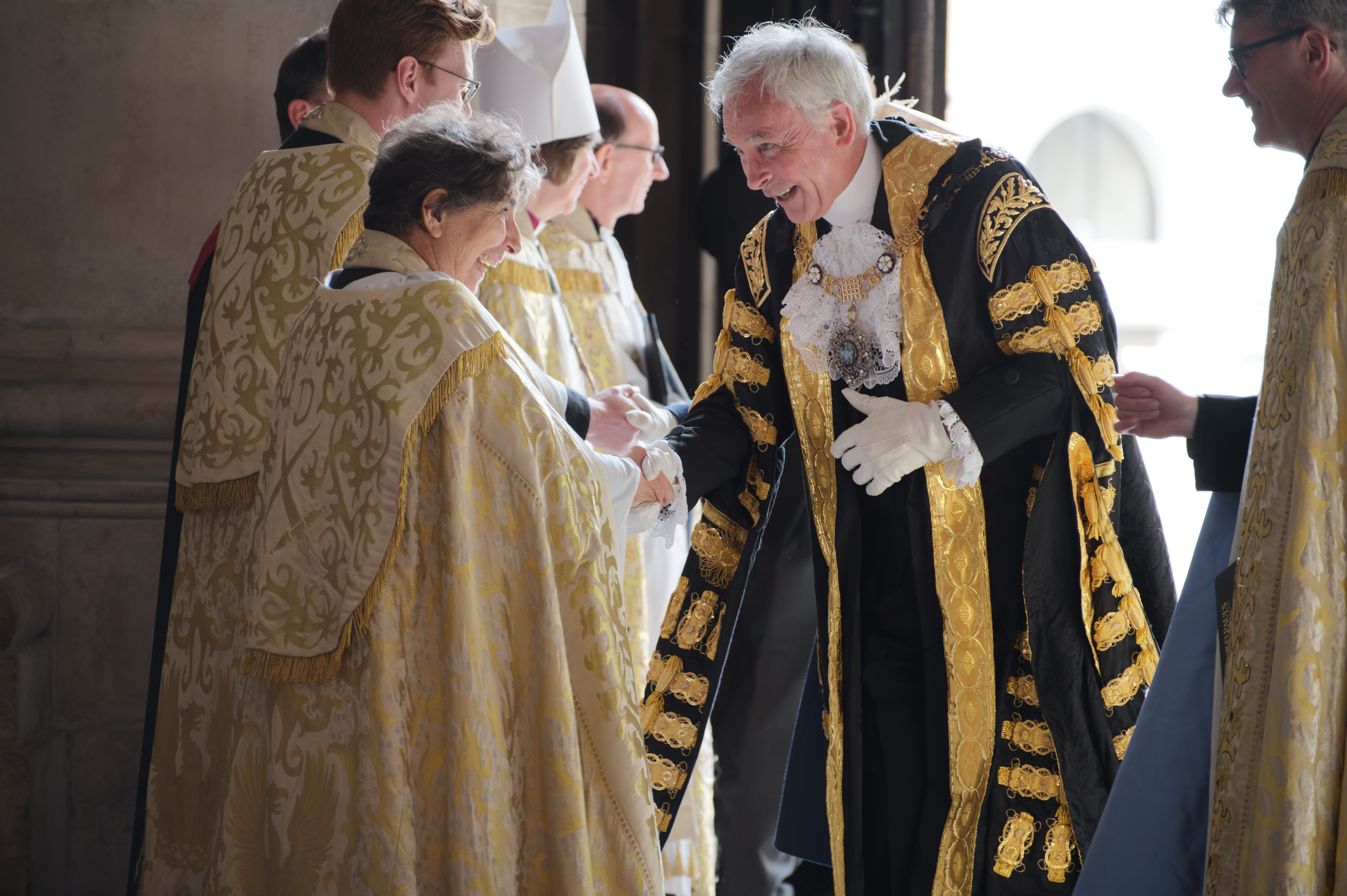 The Mayor of London, dressed in a black and gold gown, shaking someone's hand.