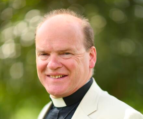 Bishop Humphrey Southern, wearing a cream-white jacket, a black shirt and a white dog collar.