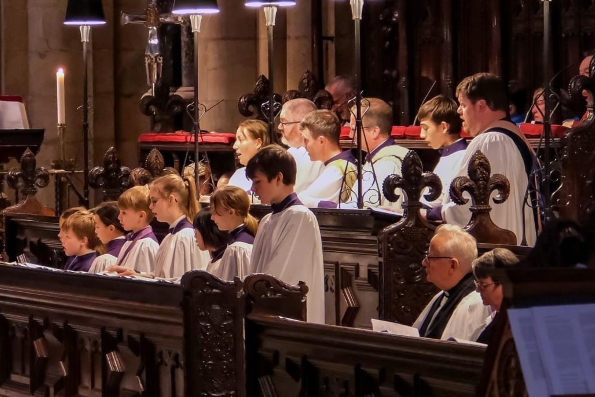 The choristers of Durham Cathedral Choir, dressed in white and singing.