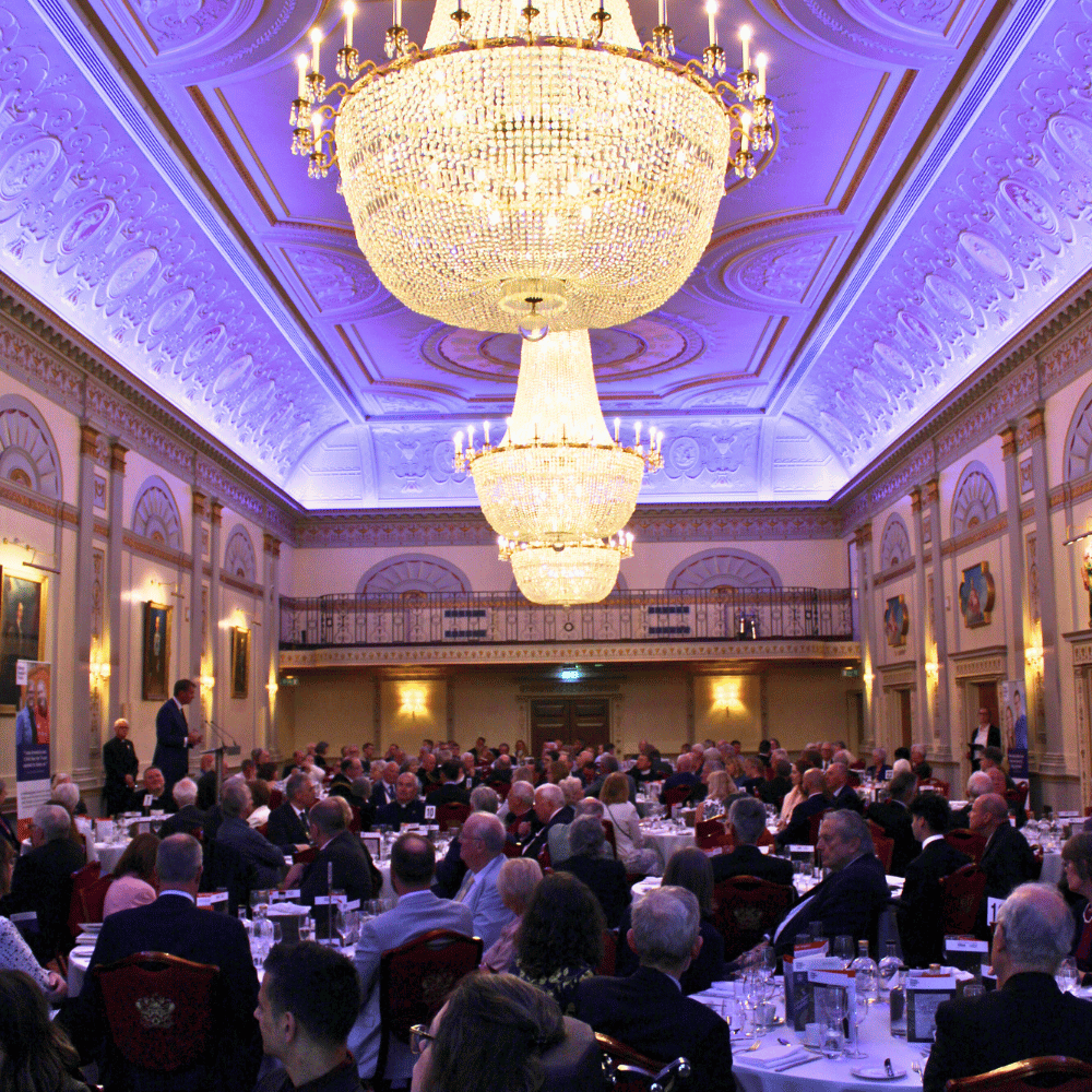 The interior of Plaisterers' Hall. Circular tables, with white tablecloth, sat around by formally-dressed guests.