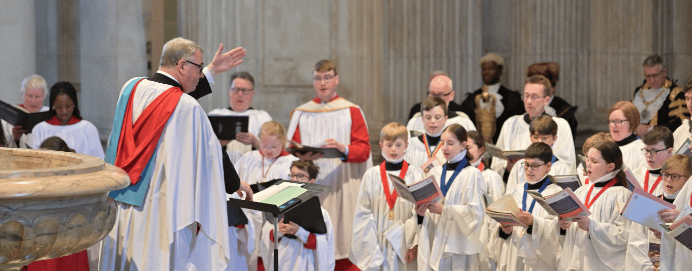 A group of choristers are being led in song by the Director of Music, Andrew Carwood.