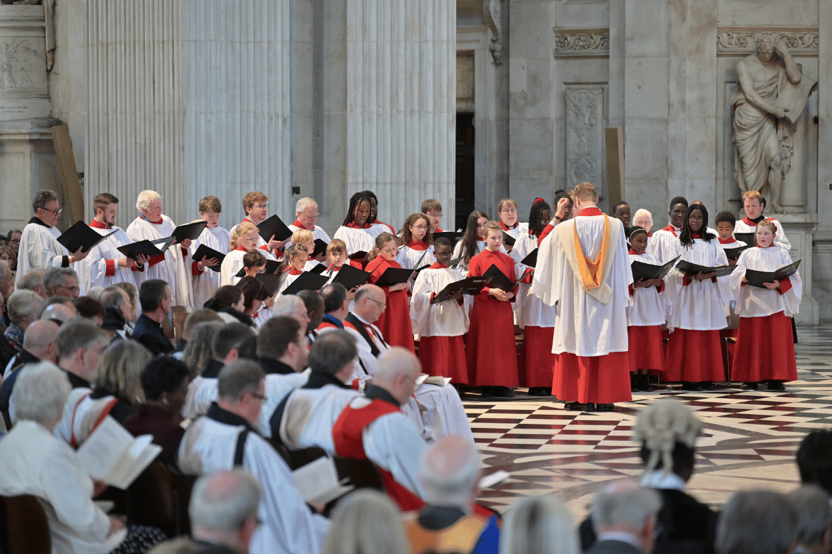 Bradford Cathedral Choir, standing on the chequered black and white tiled floor of St Paul's Cathedral.