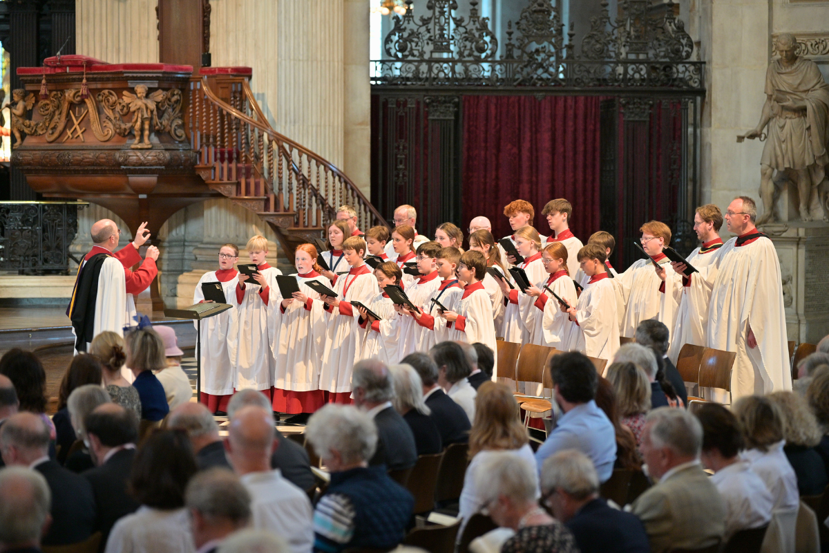Lichfield Cathedral Choir, dressed in white robes and singing to a captivated audience, sat on wooden chairs in front of them.