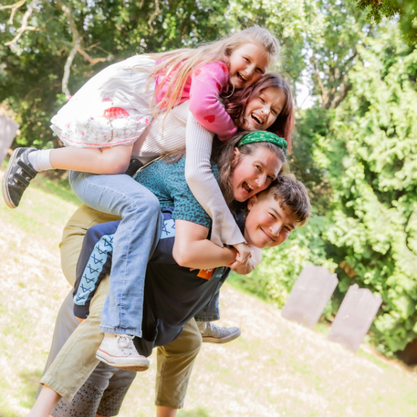 Theo is giving his mother and two younger sisters a piggy-back.