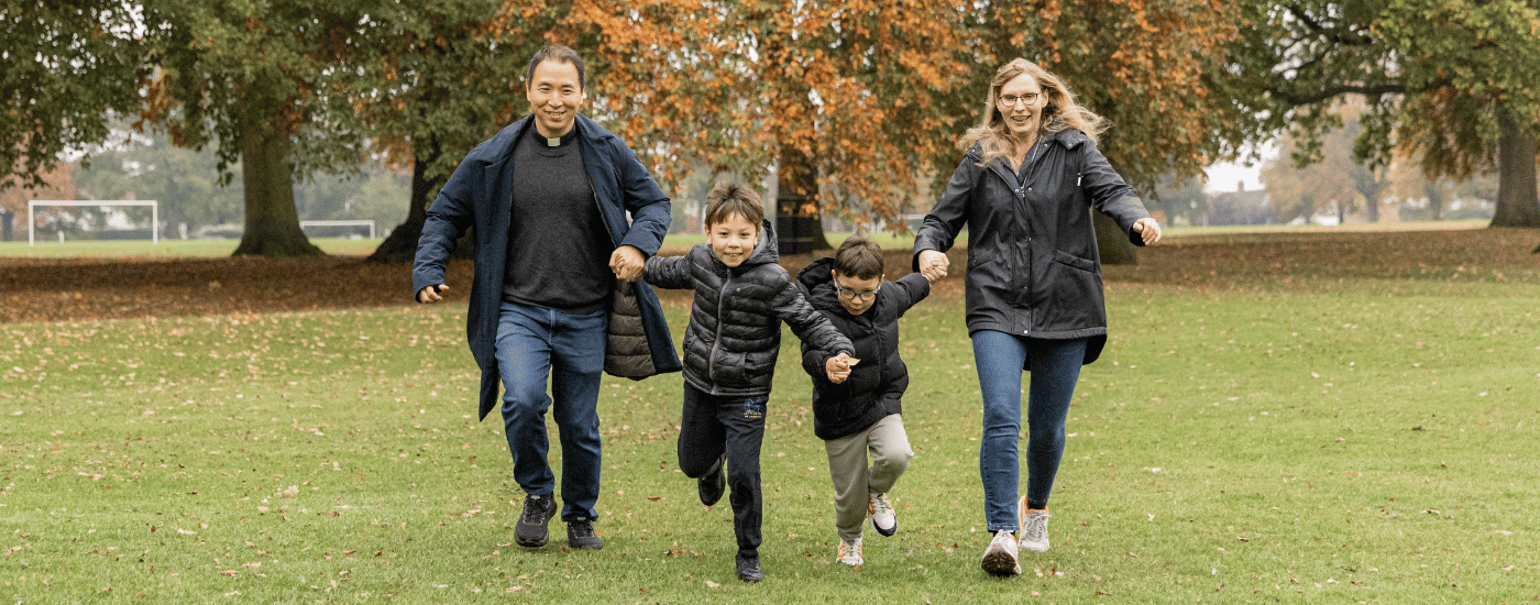 Jun, his wife and sons are running through the park, dressed in their winter coats.