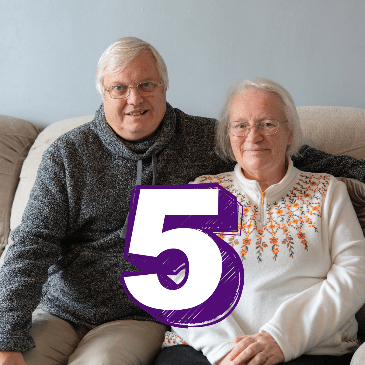 A man and a woman are sat on their sofa in their living room. Text reads: five.