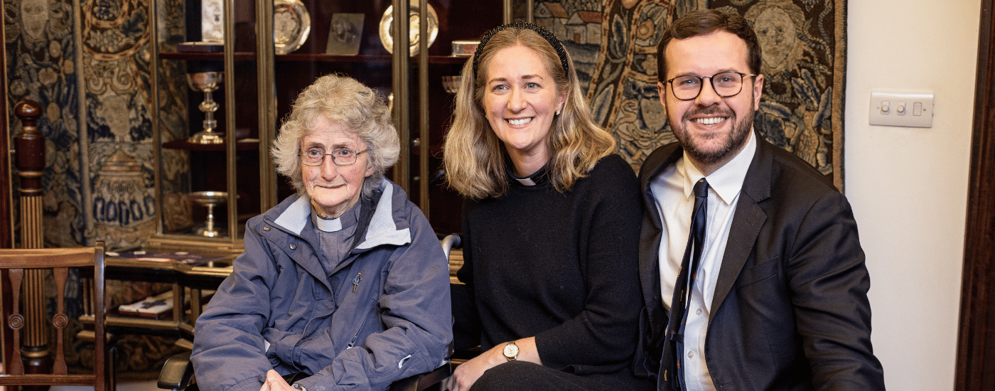 A man and a woman are crouched beside a woman in a wheelchair.