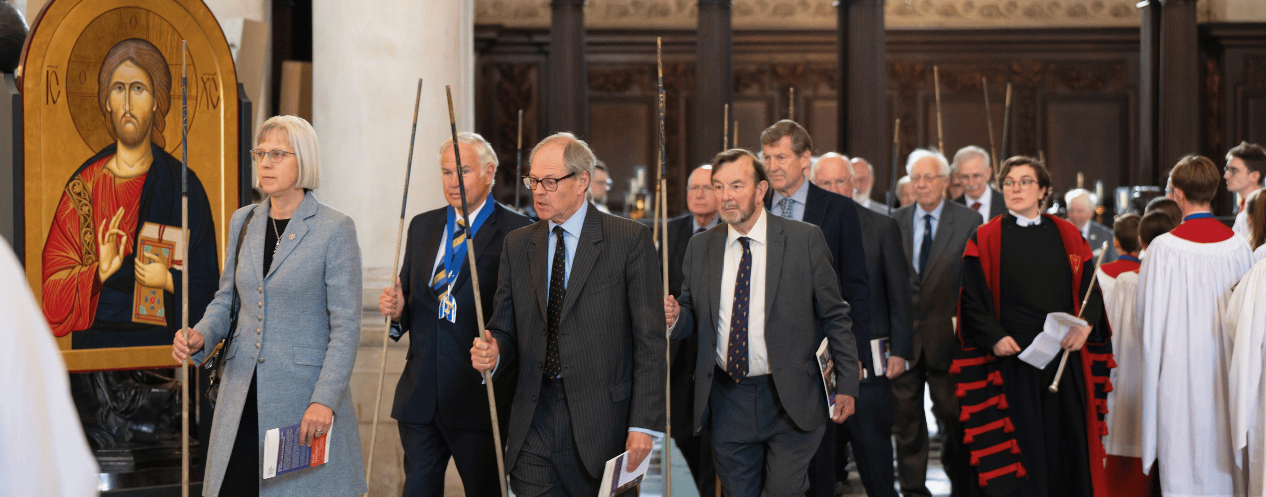Our Stewards are dressed formally, and walking from The Chapel of St Michael and St George to the main aisle of the cathedral, carrying wands (long, wooden ceremonial poles) in their right hands.