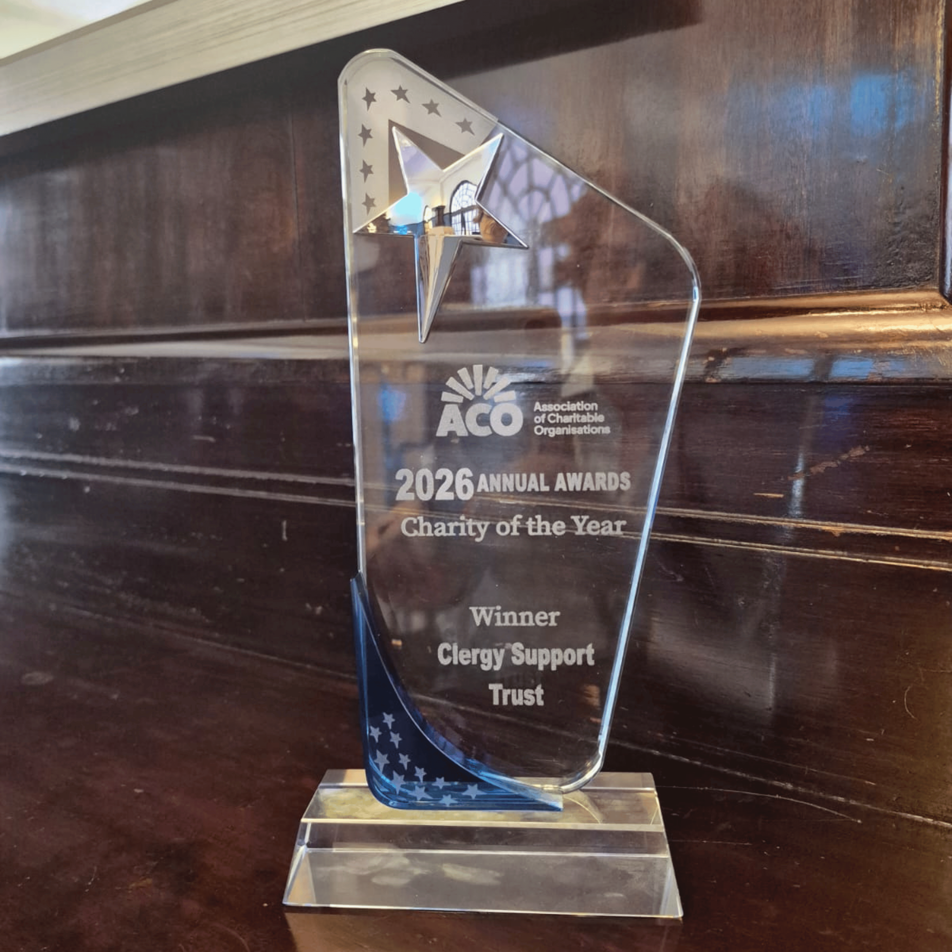 A glass award, sitting on a polished wooden shelf.