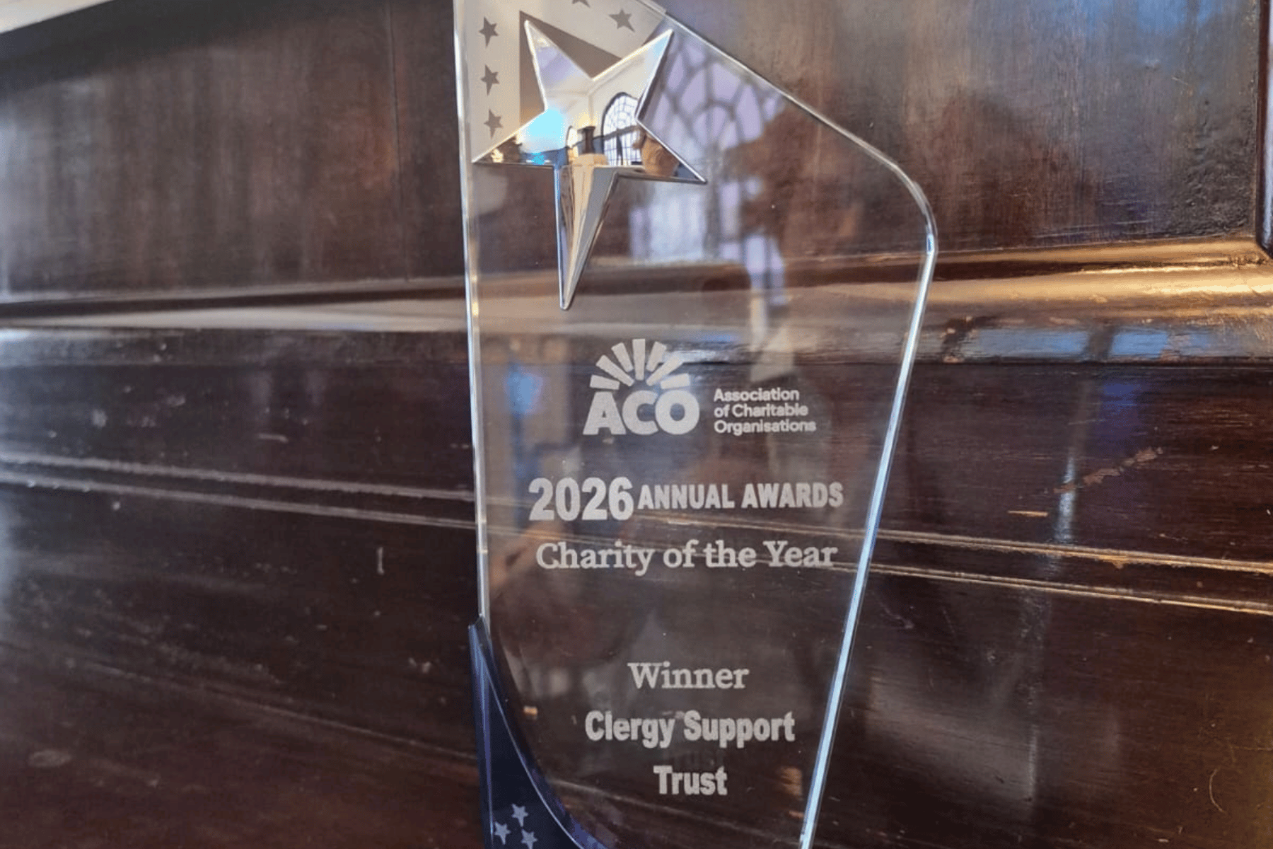 A glass trophy, sat on a wooden ledge.