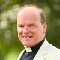 Bishop Humphrey Southern, wearing a cream-white jacket, a black shirt and a white dog collar.