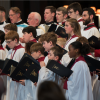 Choristers of different ages, performing together. They are dressed in white and red robes.