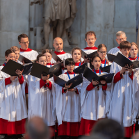 St Albans Cathedral Choir are dressed in white and red robes, as choristers of all ages sing together.