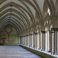 Stone pillars, illuminated by natural light, line a paved path in an Oxford University college.